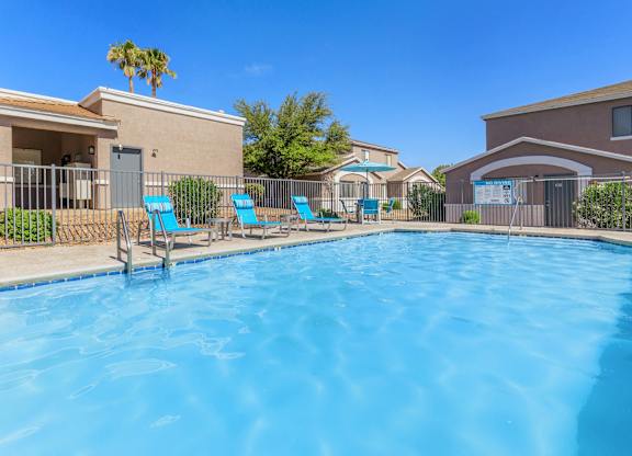 A swimming pool surrounded by chairs and a fence.