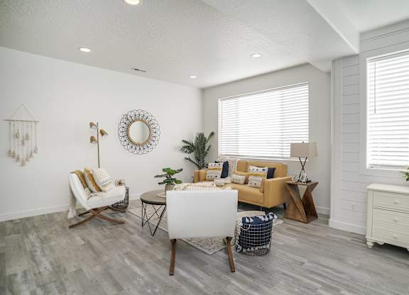 the living room of a manufactured home with white walls and a couch and chairs