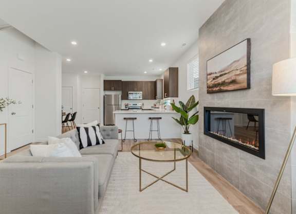 A modern living room with a grey couch and a fireplace.
