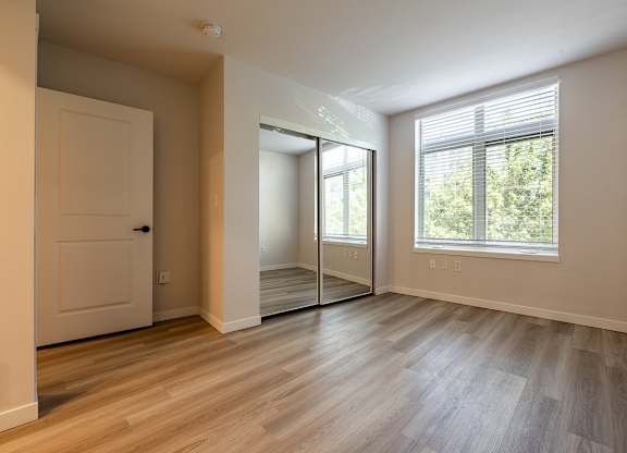 A room with a white door, a window with blinds, and a sliding glass door.