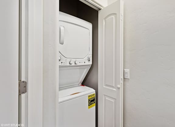 A white fridge is in a narrow space between a door and a wall.