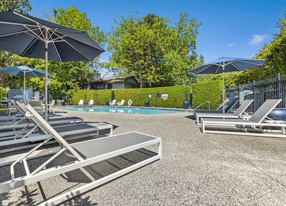 A sunny day at the pool with lounge chairs and umbrellas.