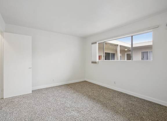 A room with a carpeted floor and a window.