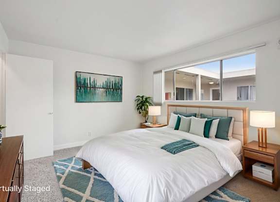 A bedroom with a large bed and a painting on the wall.