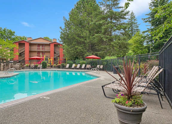 A pool area with a red umbrella and a black fence.