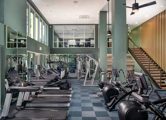 A gym with treadmills, exercise bikes, and a staircase.
