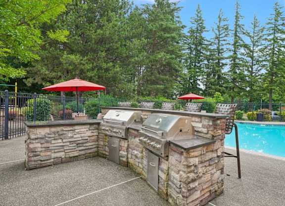 A backyard with a pool and a stone barbecue.