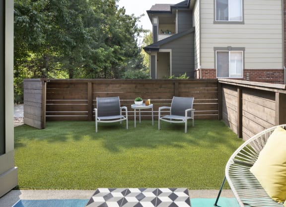 a backyard with a wooden fence and a patio with two chairs and a table