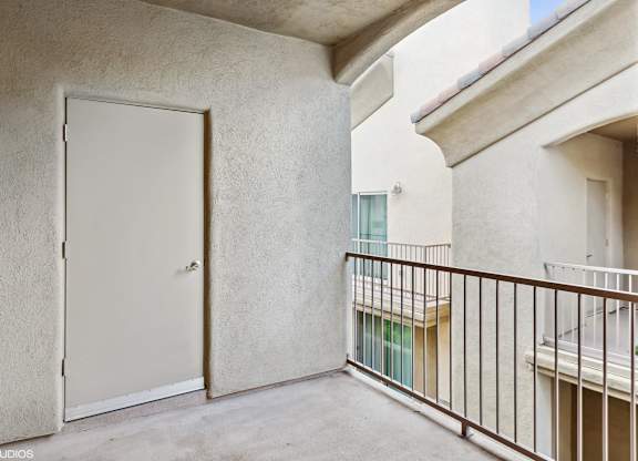 A white door is on the left side of a balcony.