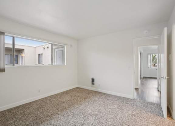 A spacious room with a carpeted floor and a window overlooking a balcony.