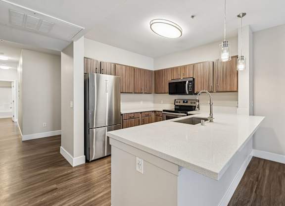 A kitchen with a white countertop and wooden cabinets.