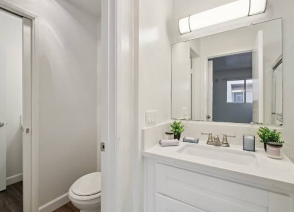 A white bathroom with a toilet, sink, and mirror.