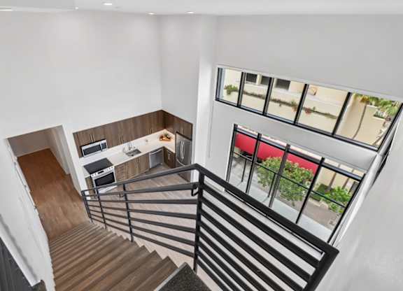 A staircase with a black railing leads to a living room and kitchen area.