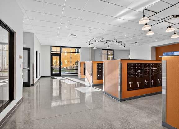A modern office lobby with a glass wall and a row of orange cubicles.