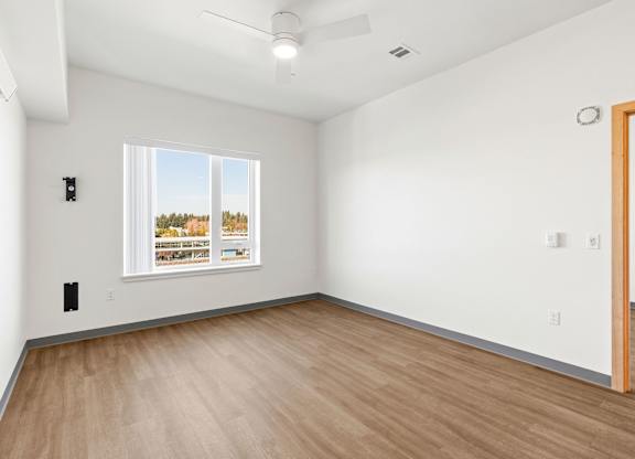 A room with a window showing a view of trees and buildings outside.