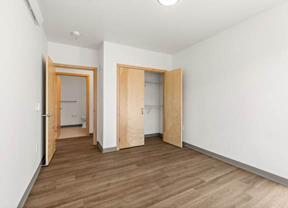 A room with wooden floors and two open doors.