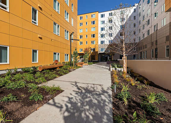 A long concrete pathway leads between two buildings.