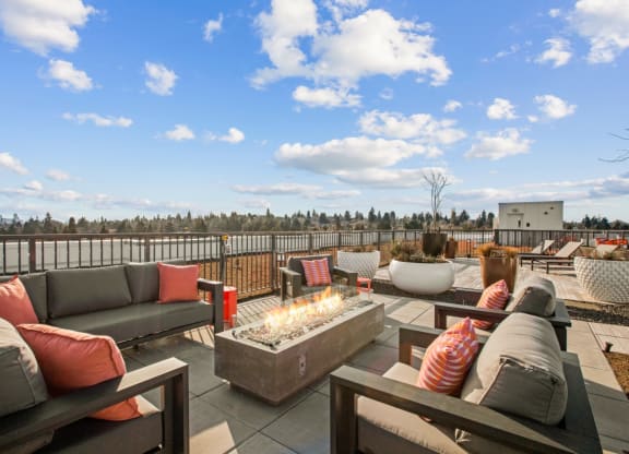 a rooftop patio with couches and a fire pit