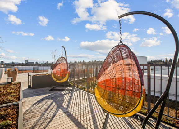 a pair of orange and yellow hammock chairs on a roof top patio
