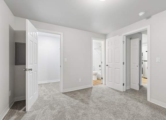 A spacious, empty room with carpeted floor and white walls.