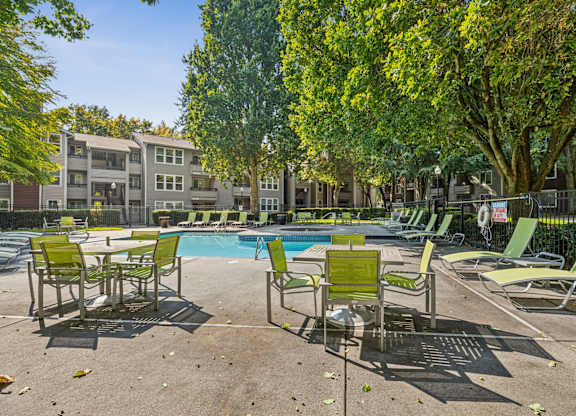A pool surrounded by chairs and trees.