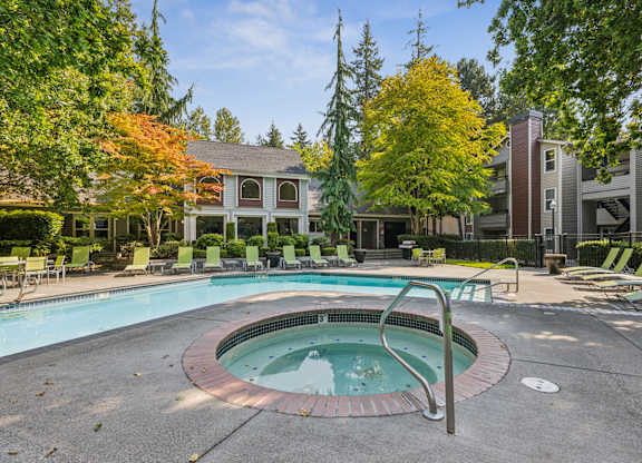 A swimming pool surrounded by trees and chairs.