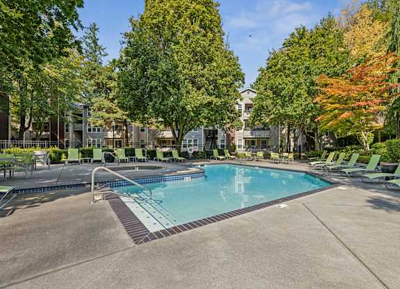 A swimming pool surrounded by trees and lounge chairs.