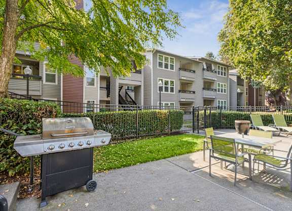 A barbecue grill is in the foreground of a residential area with apartment buildings in the background.