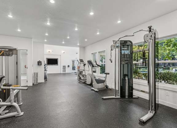 A spacious gym with various exercise equipment and a mirror on the wall.