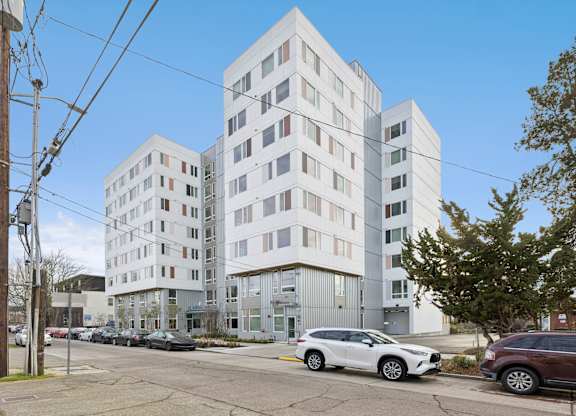 A white car is parked in front of a white building.