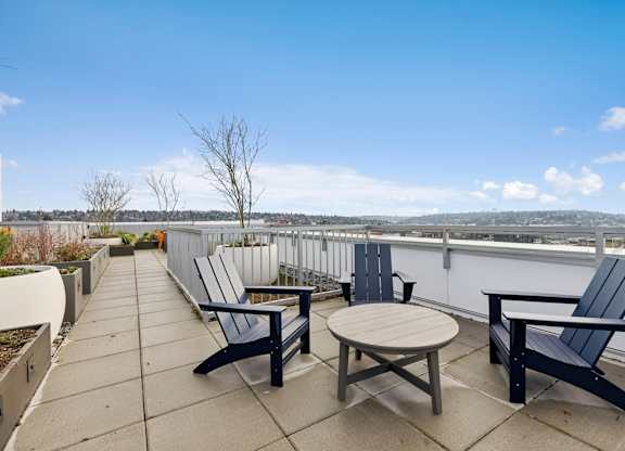 A patio with a table and chairs overlooking a cityscape.