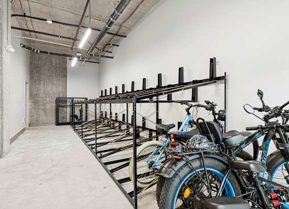 A row of bikes are parked in a bike rack.