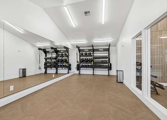 A gym with wooden floors and mirrors on the wall.