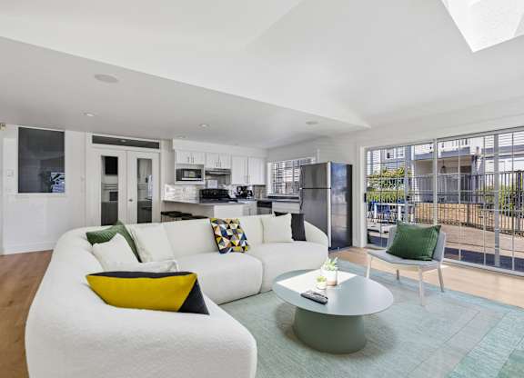 A modern living room with a white couch and a glass table.