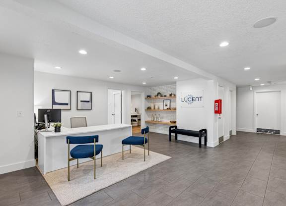 A spacious office with a white reception desk and blue chairs.
