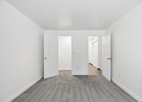 A hallway with a carpeted floor and white walls.