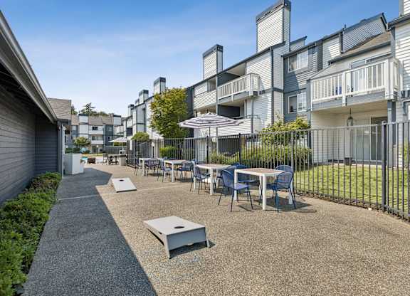 A patio with a table and chairs is surrounded by a fence and buildings.