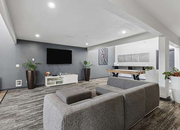 A modern living room with grey sofas and a television.