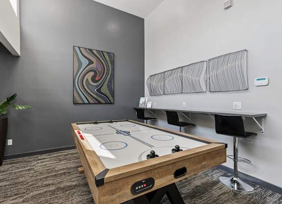 A pool table in a room with a plant and a painting on the wall.