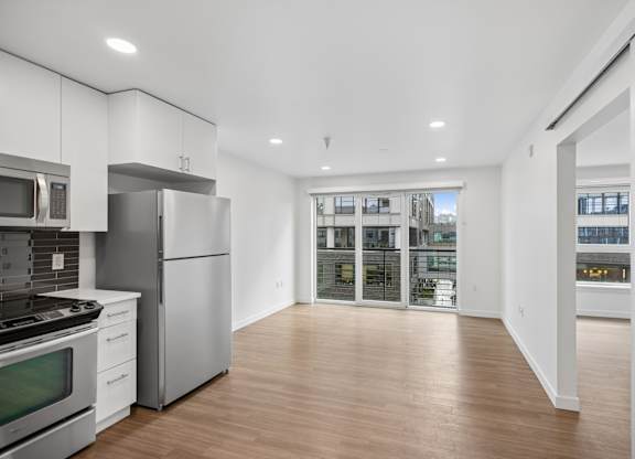 A modern kitchen with stainless steel appliances and wooden floors.