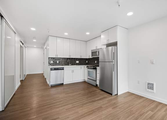 A modern kitchen with stainless steel appliances and wooden floors.