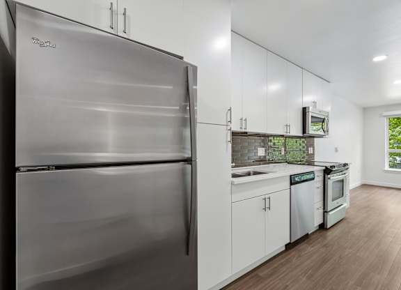 A modern kitchen with a stainless steel refrigerator and white cabinets.