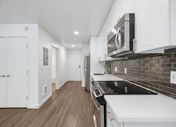 A modern kitchen with white cabinets and a black stove top.