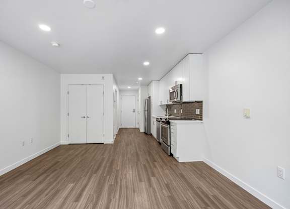A long hallway with white walls and wood flooring.