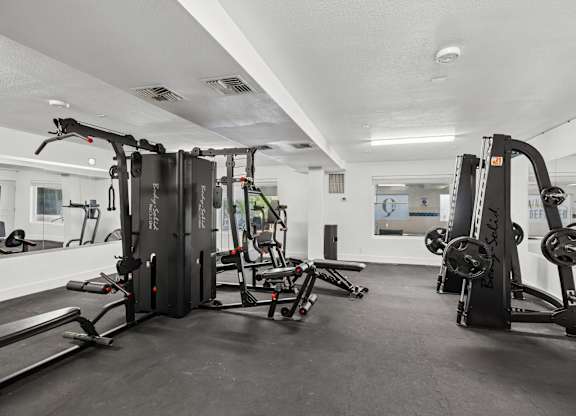 A gym with a variety of equipment including a treadmill, a squat rack, and a bench press.