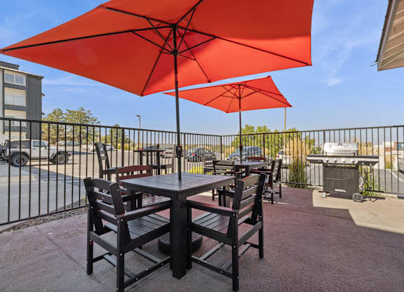 A patio with a table and chairs under a red umbrella.