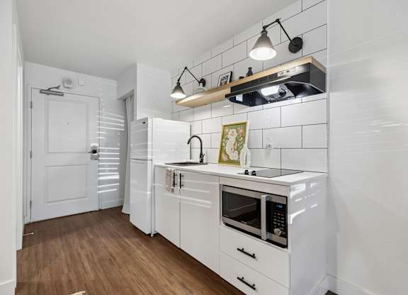 A white kitchen with a microwave, oven, and stove top.