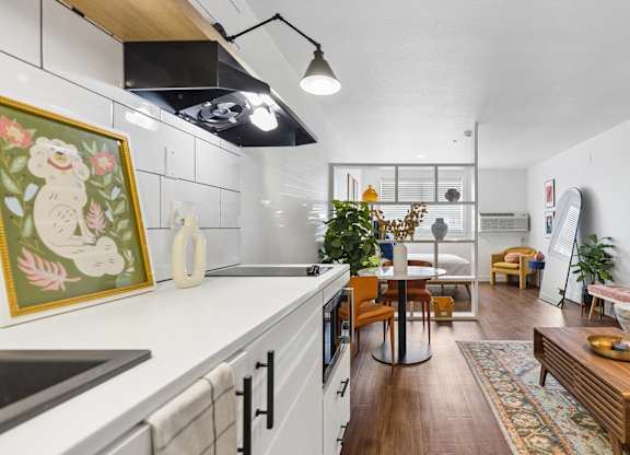 A kitchen with a white counter top and wooden floors.