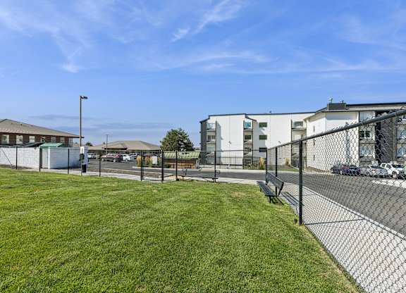 A grassy area with a fence and buildings in the background.