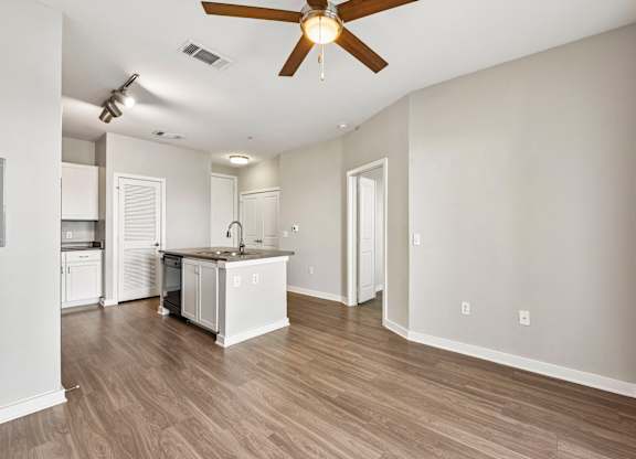 A kitchen with white cabinets and a wooden floor.